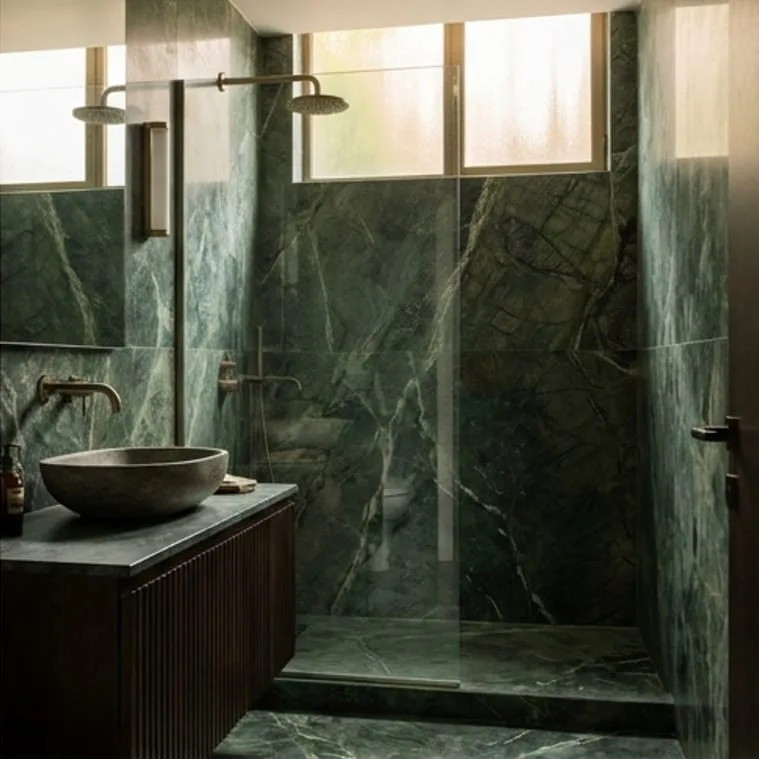 Yeşil damarlı mermer duvarlı banyoda taş lavabo ve oluklu ahşap dolap