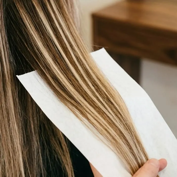 Uzun saç üzerinde elle sürülmüş sarı balayaj tutamları
