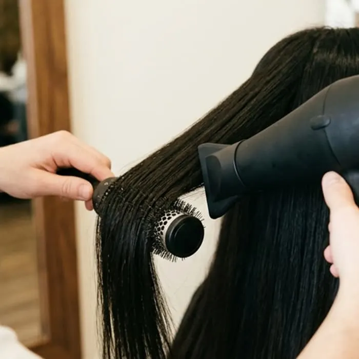 Yuvarlak fırça ve fön makinesiyle düzleştirilen uzun koyu saç