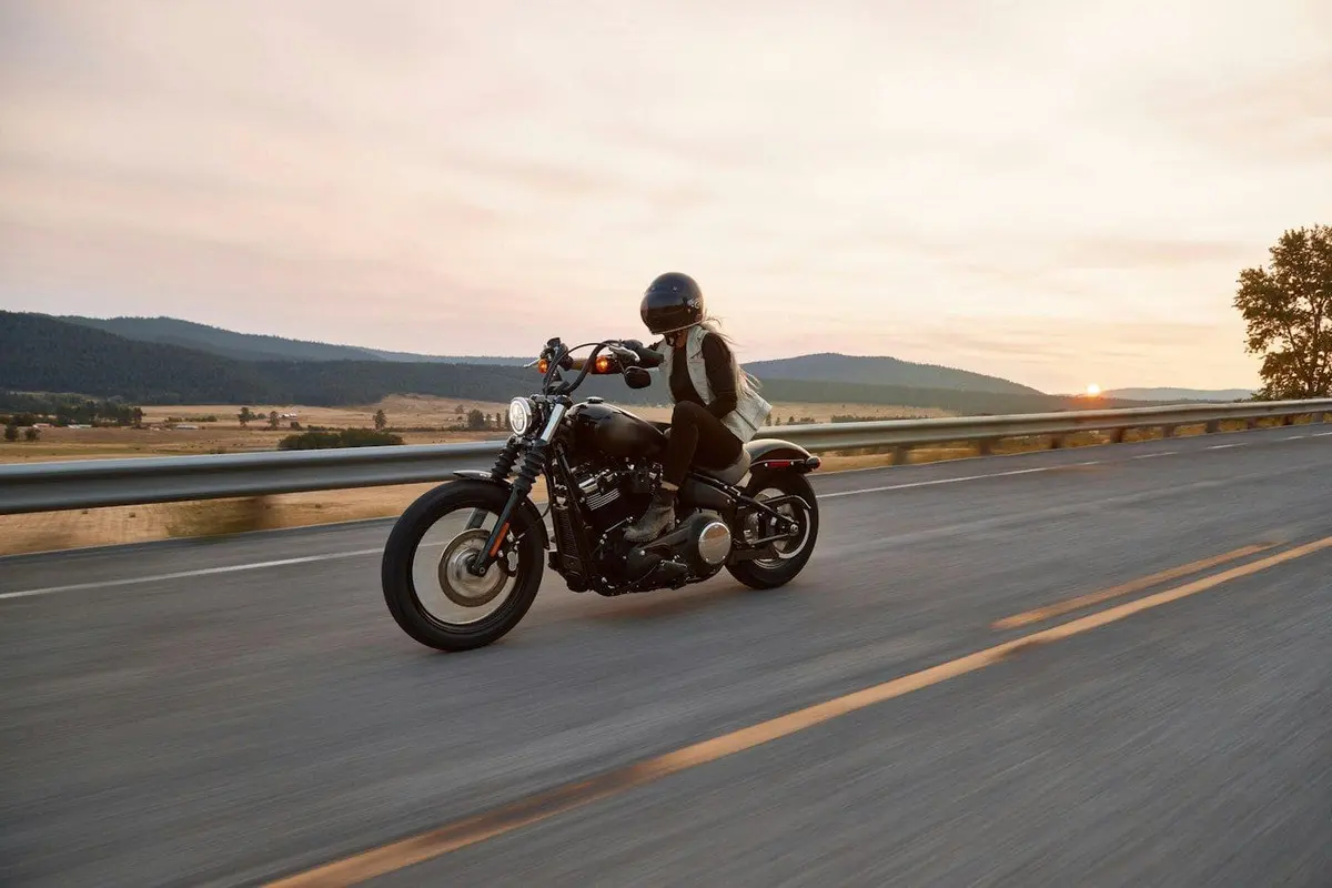 Gün batımında açık yolda büyük motosiklet süren kasklı sürücü